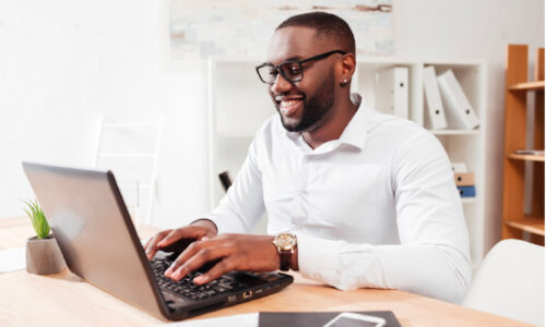 Man smiling while working on a laptop